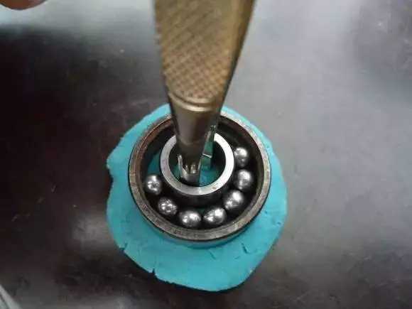 用鑷子或別的相近的物體越過內(nèi)圈，同時(shí)向滾珠的方向用力頂住